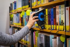 Eine Sitzgruppe mit einem Tisch und zwei Sesseln vor einem vollen Bücherregal in der Gemeindebücherei