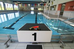 Foto des Sprungbocks mit der Nummer "1" im SimmBad. Auf dem Bock liegt eine gelb-orange Taucherbrille, im Hintergrund ist das Wasser zu sehen.