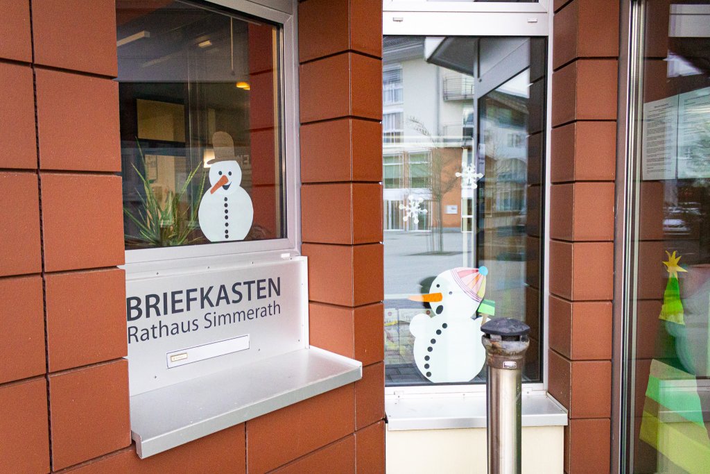 Schneemänner aus Papier an den Scheiben des Rathauses