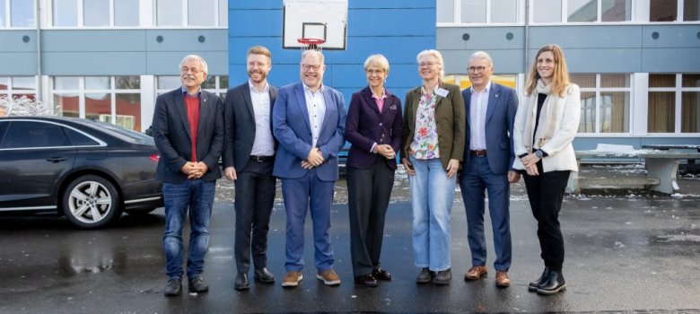 Gruppenfoto vor dem Schulgebäude mit v. l. n. r.: Klaus Onasch (Roetgen), Daniel Scheen-Pauls MdL, Stephan Cranen (Hürtgenwald), Ministerin Dorothee Feller, Schulleiterin Diana Hoch, Bernd Goffart (Simmerath), Dr. Carmen Krämer (Monschau)