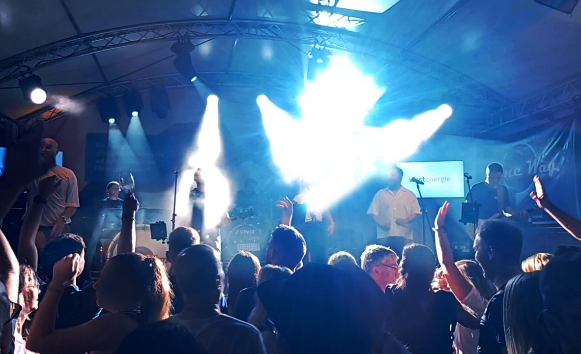 Feiernde Menschen vor einer Bühne im Scheinwerferlicht