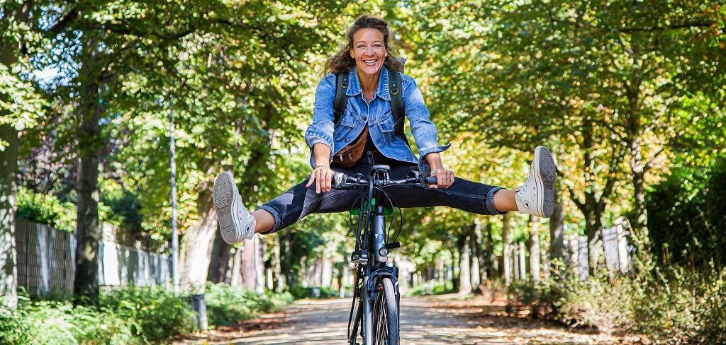 Frau fährt auf dem Fahrrad durch eine Allee