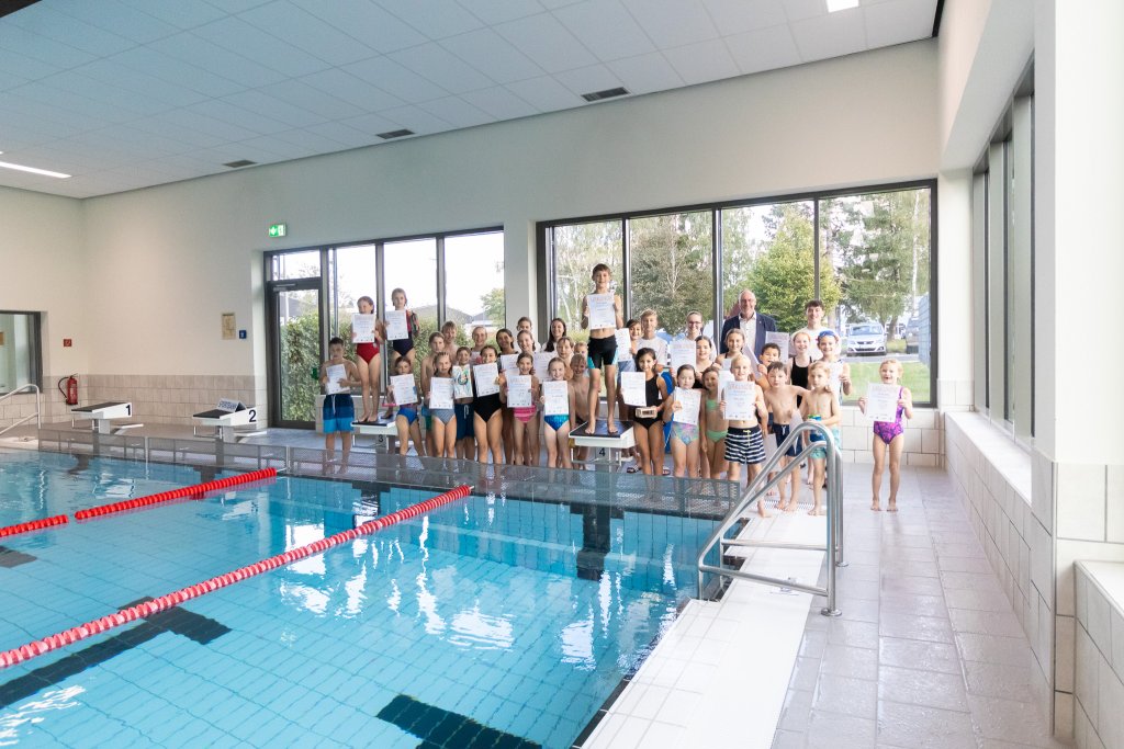 Gruppenfoto der Teilnehmerinnen und Teilnehmer am Beckenrand mit Urkunden