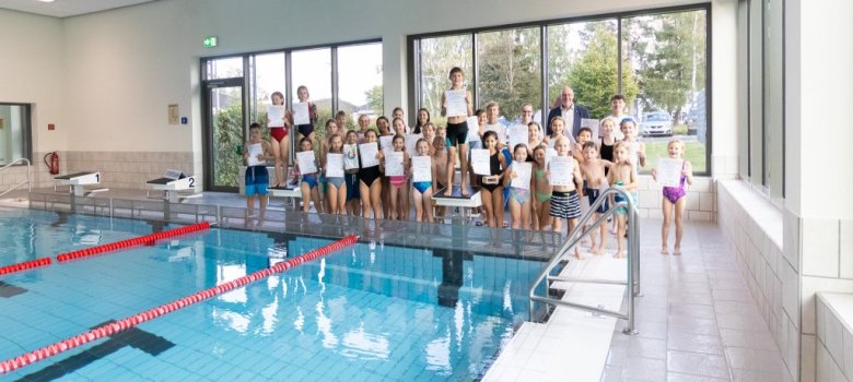 Gruppenfoto der Teilnehmerinnen und Teilnehmer am Beckenrand mit Urkunden