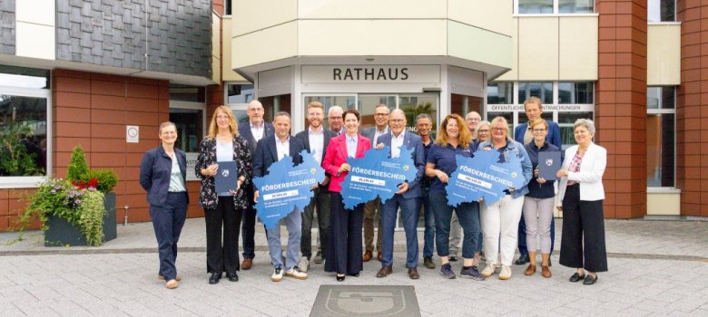 Gruppenfoto vor dem Rathaus mit allen Förderbescheidempfängern und der MInisterin