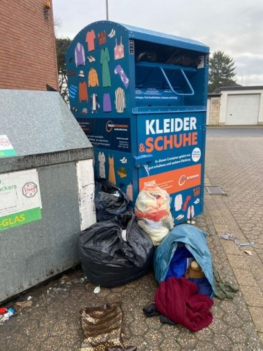 Alterkleidercontainer, vor dem Säcke abgelagert wurden