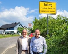 Ortvorsteher und Bürgermeister am Ortsschild von Rurberg