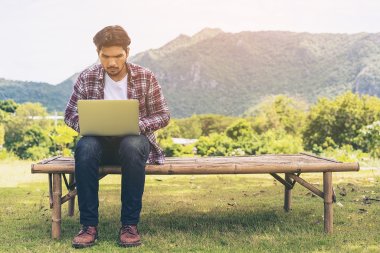 Mann sitzt mit Laptop auf einer Bank